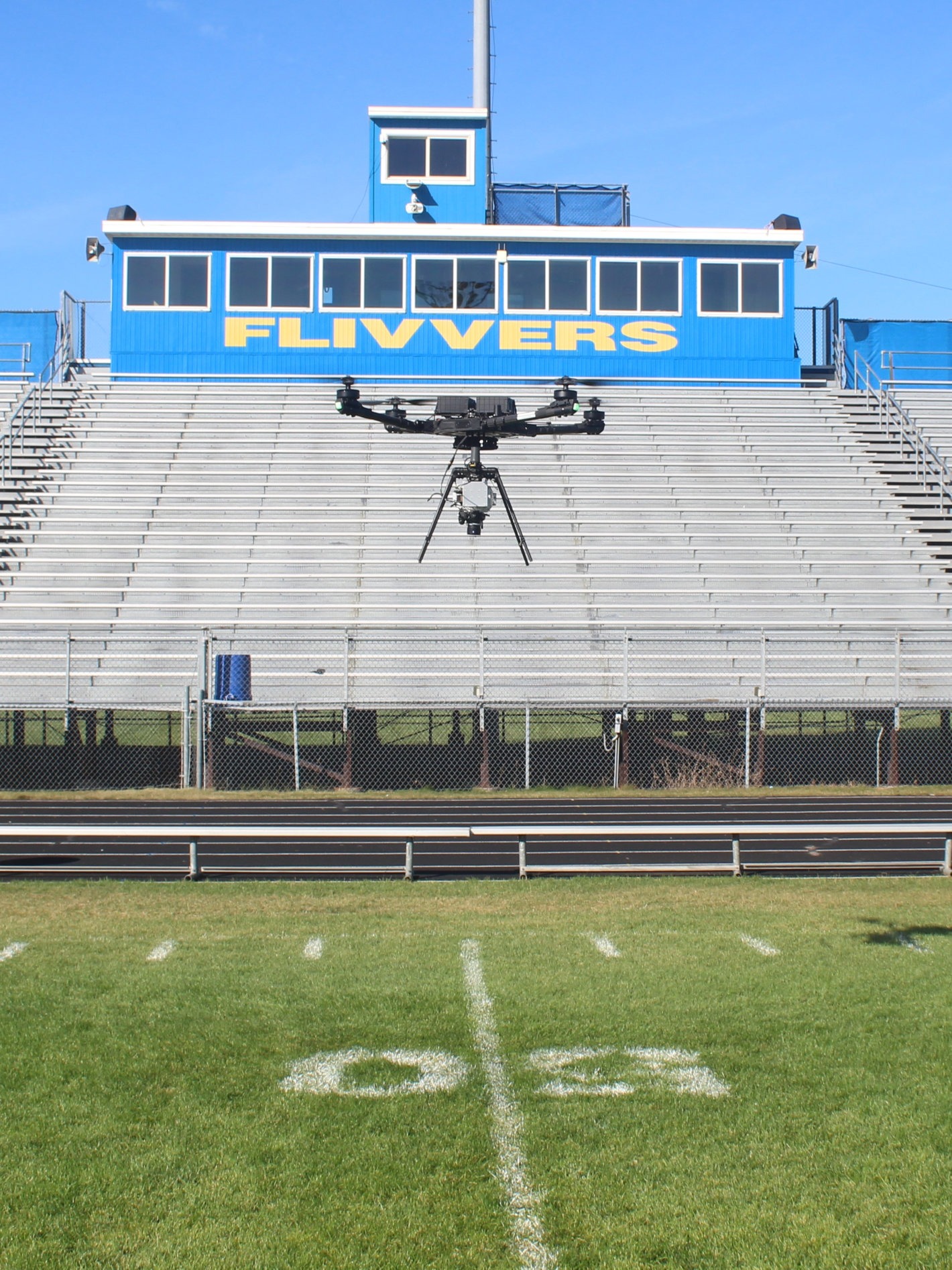 Drone flying over football field Drone flying over football field in front of bleachers at Kingsford high school